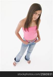 Young girl standing with hands in pockets frowning