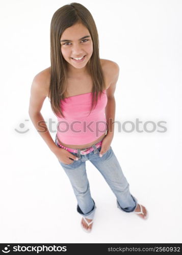 Young girl standing with hands in pockets smiling