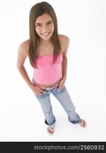 Young girl standing with hands in pockets smiling