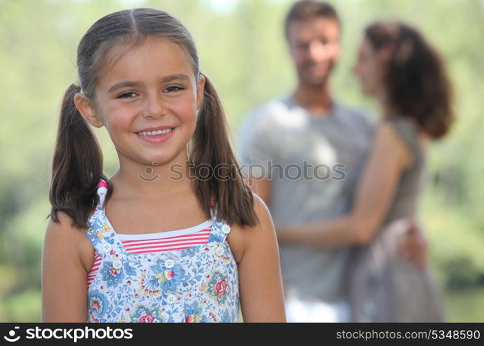 Young girl strolling in the park with her parents