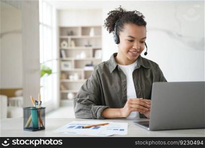 Young girl student wearing wireless headphones, learning online at laptop at home. Biracial teen schoolgirl wearing a headset, watches educational webinar. Distance education, homeschooling concept.. Biracial young girl student in headset learning online at laptop at home. Distance education