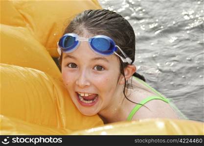 Young girl swimming with float in lake during summer time