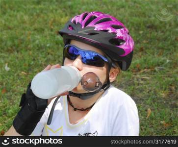 Young girl taking a break from rollerblading drinking water
