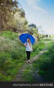 Young girl taking a walk in the field with a blue umbrella