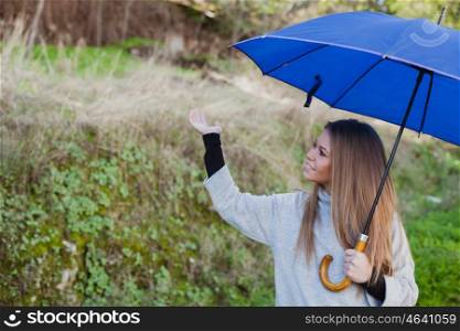 Young girl taking a walk in the field with a blue umbrella