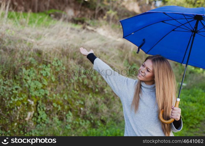 Young girl taking a walk in the field with a blue umbrella