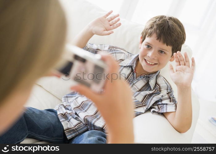 Young girl taking picture of smiling young boy with camera phone indoors