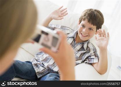 Young girl taking picture of smiling young boy with camera phone indoors