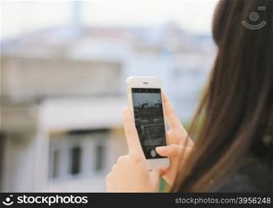 Young girl taking picture with smartphone on city