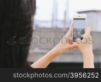 Young girl taking picture with smartphone on city