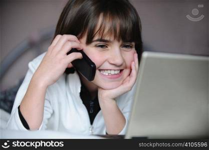 young girl talking on mobile phone while on computer