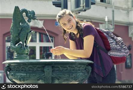 Young girl travel and drinking water from the fountain
