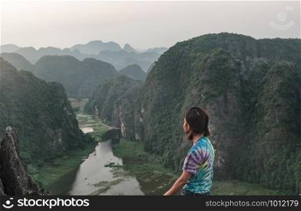 Young girl travelers standing watch the beauty of nature. viewpoint at Hang Mua, Ninh Binh in Vietnam.