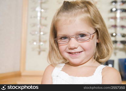 Young girl trying on eyeglasses at optometrists smiling