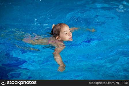 Young girl trying to hold on water surface at swimming pool