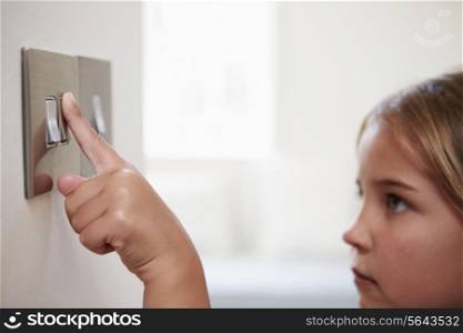 Young Girl Turning Off Light Switch