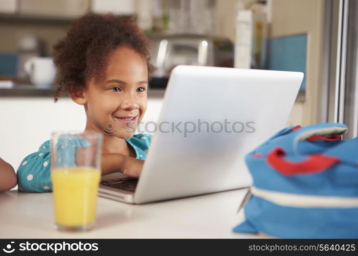 Young Girl Using Laptop To Do Homework At Table
