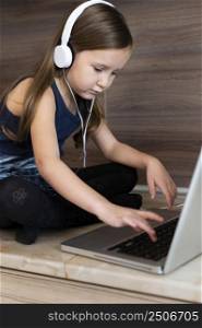 young girl using laptop with headphones