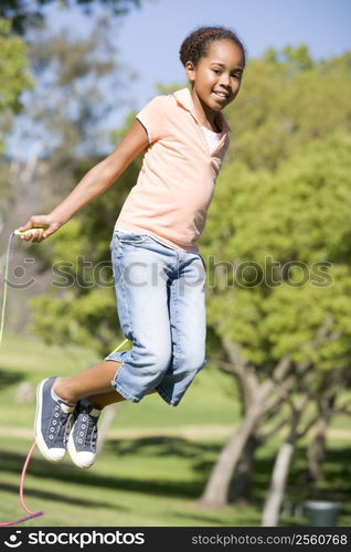 Young girl using skipping rope outdoors smiling