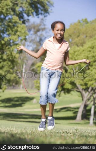 Young girl using skipping rope outdoors smiling