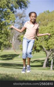 Young girl using skipping rope outdoors smiling