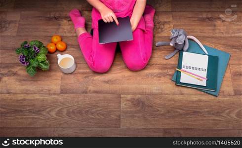 Young girl using tablet top view on wooden floor with copy space