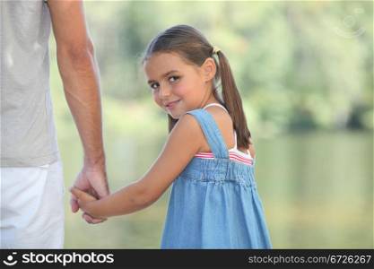 Young girl walking by the lake with her parents