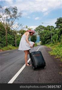 young girl walking down the road with a suitcase
