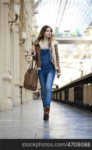 Young girl walking in denim overalls in the shop