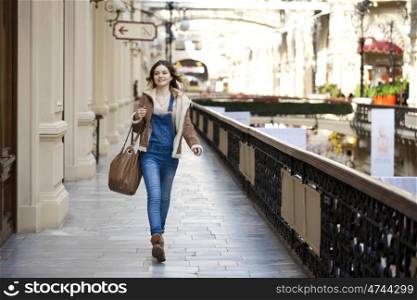 Young girl walking in denim overalls in the shop