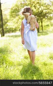 Young Girl Walking Through Summer Field Carrying Teddy Bear