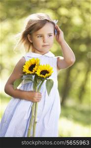 Young Girl Walking Through Summer Field Holding Sunflower