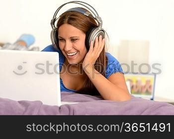 Young girl watching movie on laptop lying on bed