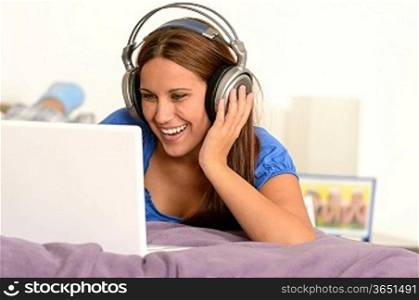 Young girl watching movie on laptop lying on bed