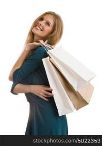 Young girl wearing elegant dress posing against white background. Holding shopping bags and looking upwards