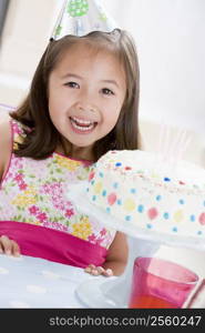 Young girl wearing party hat with birthday cake smiling