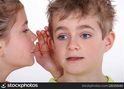 Young girl whispering into a boy&acute;s ear