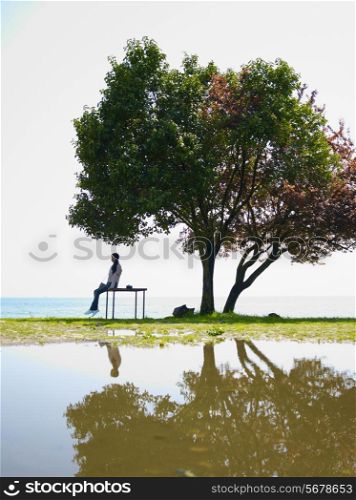Young girl with a beautiful tree reflected in a puddle