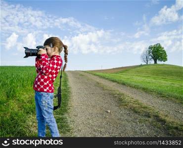 Young girl with a big camera in rural Switzerland taking pictures of the scenery.