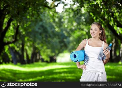 Young girl with a bottle of water and gymnastic mat