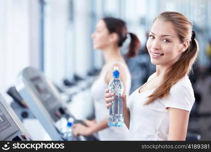 Young girl with a bottle of water on the treadmill