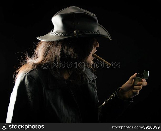 Young girl with a cigar in her mouth wearing black leather jacket and hat and holding a lighter