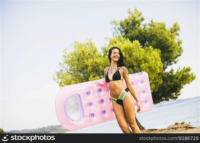 Young girl with a mattress on the beach