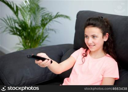 Young girl with a remote control on her sofa at home
