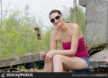 Young girl with a skewer and barbecue. A young girl happily holding a skewer strung with a barbecue