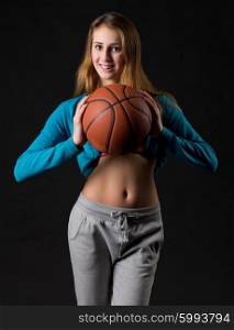Young girl with basketball ball on black