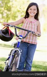 Young girl with bicycle outdoors smiling