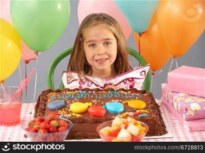 Young girl with birthday cake and gifts at party