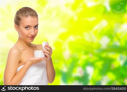 Young girl with body cream jar on floral spring background