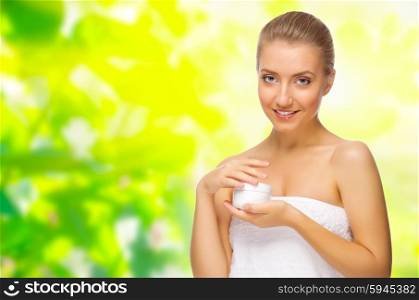 Young girl with body cream on floral spring background
